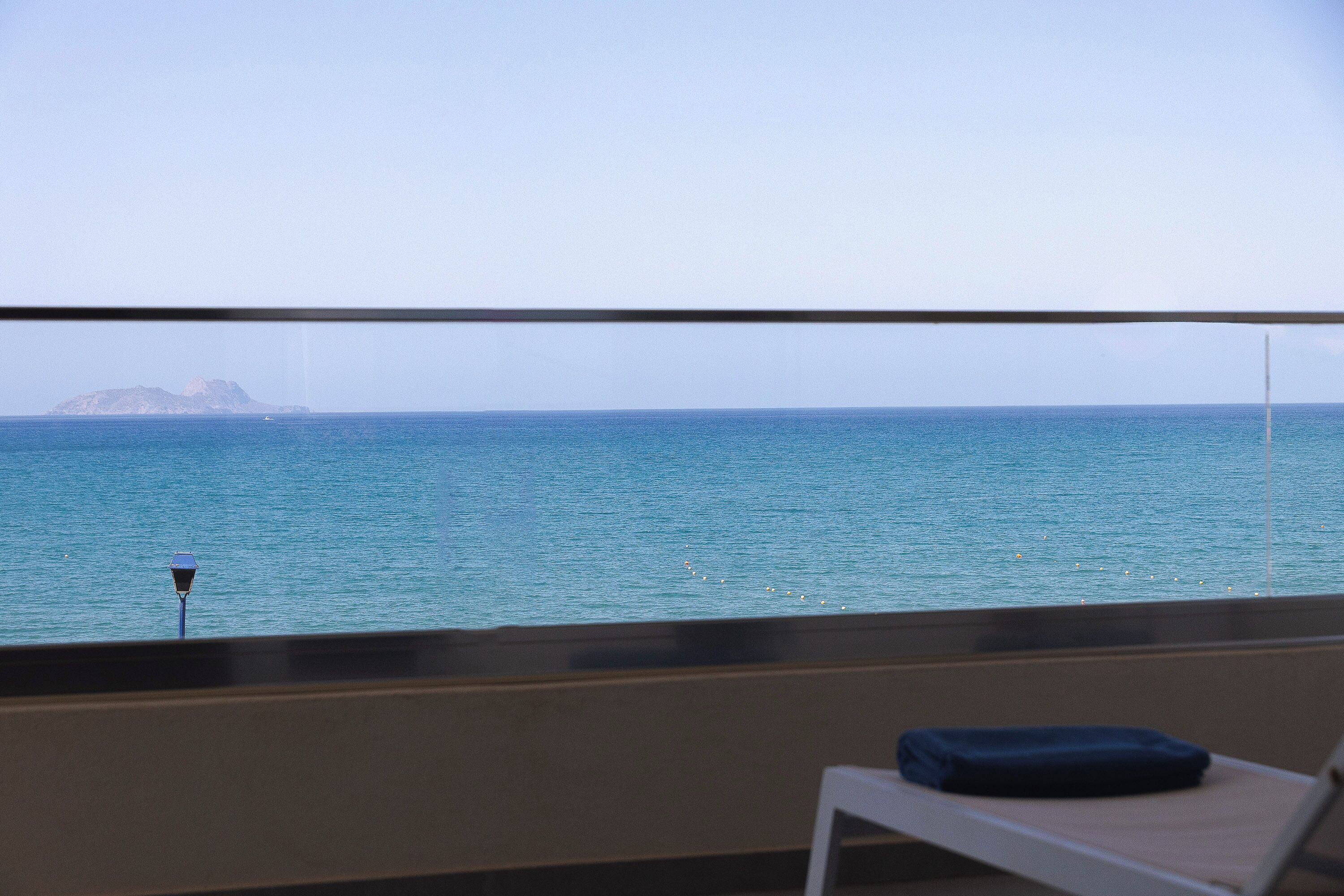 A balcony with a view of the sea and a distant island.