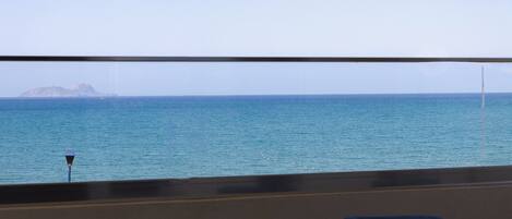 A balcony with a view of the sea and a distant island.