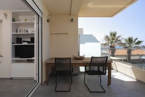 A balcony with a table and chairs, a television, and a bookshelf.