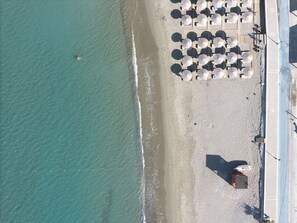 Eine Luftaufnahme eines Strandes mit Sonnenschirmen und einem Boot.