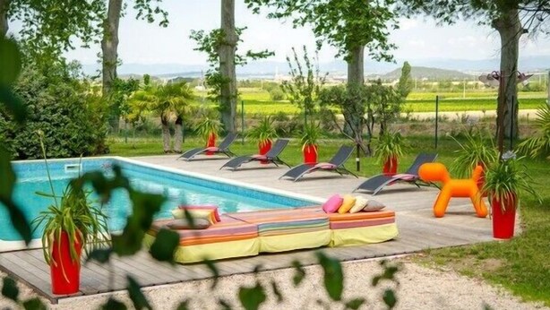 A pool area with lounge chairs and a colorful cushion. -  Large apartment with terrace in character property (Béziers)