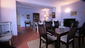 A dining area with a table set for four, surrounded by chairs, a cabinet, and a television. - Eco-Villa with garden and swimming pool UNESCO Heritage area  (Govone)