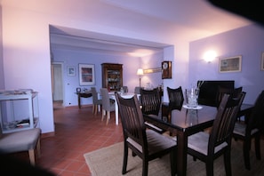 A dining area with a table set for four, surrounded by chairs, a cabinet, and a television.