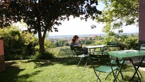 An outdoor seating area with a table and chairs, surrounded by greenery and a view of the countryside. - Eco-Villa with garden and swimming pool UNESCO Heritage area  (Govone)