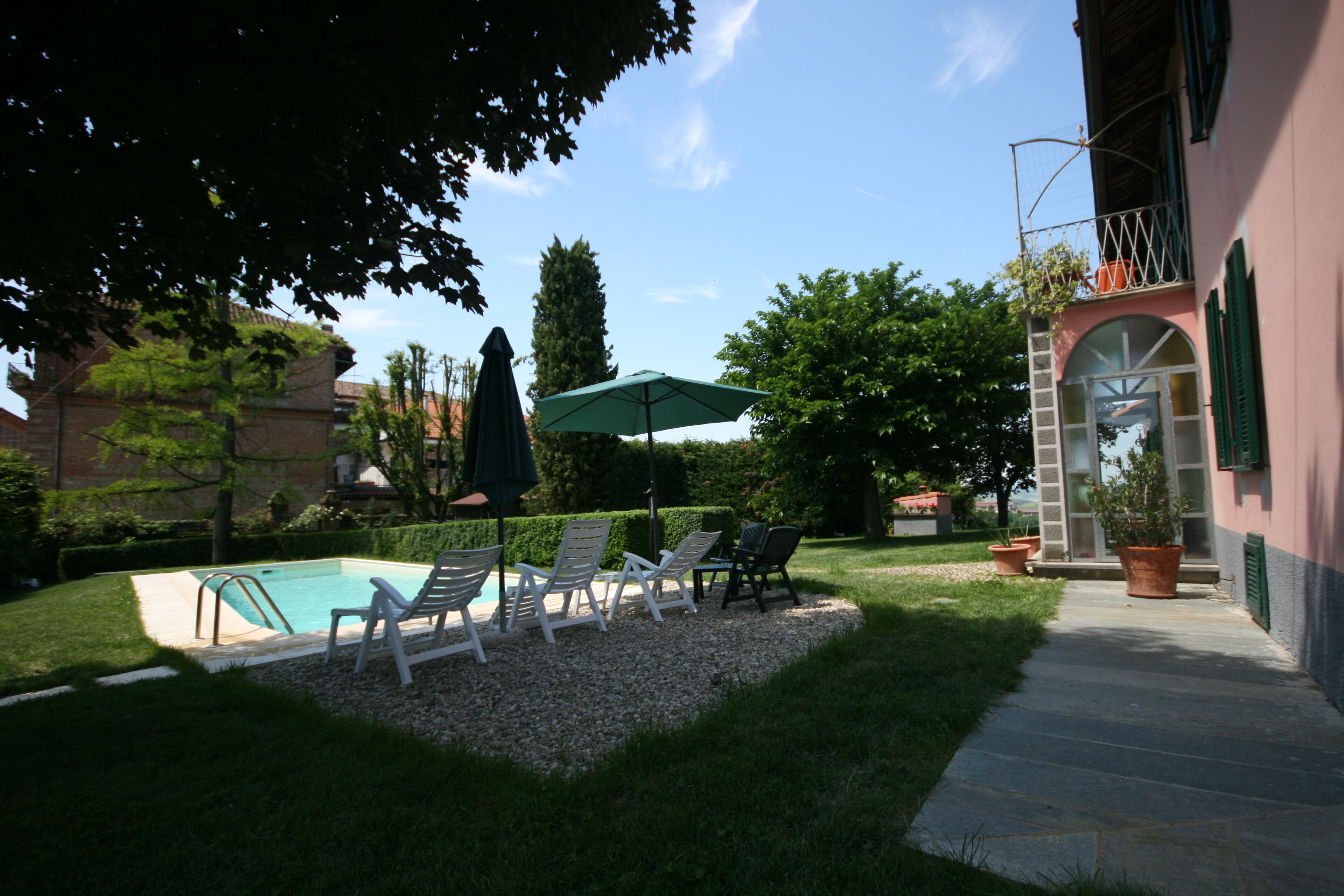 Ein Garten mit Schwimmbecken, Liegestühlen und einem Blumentopf.