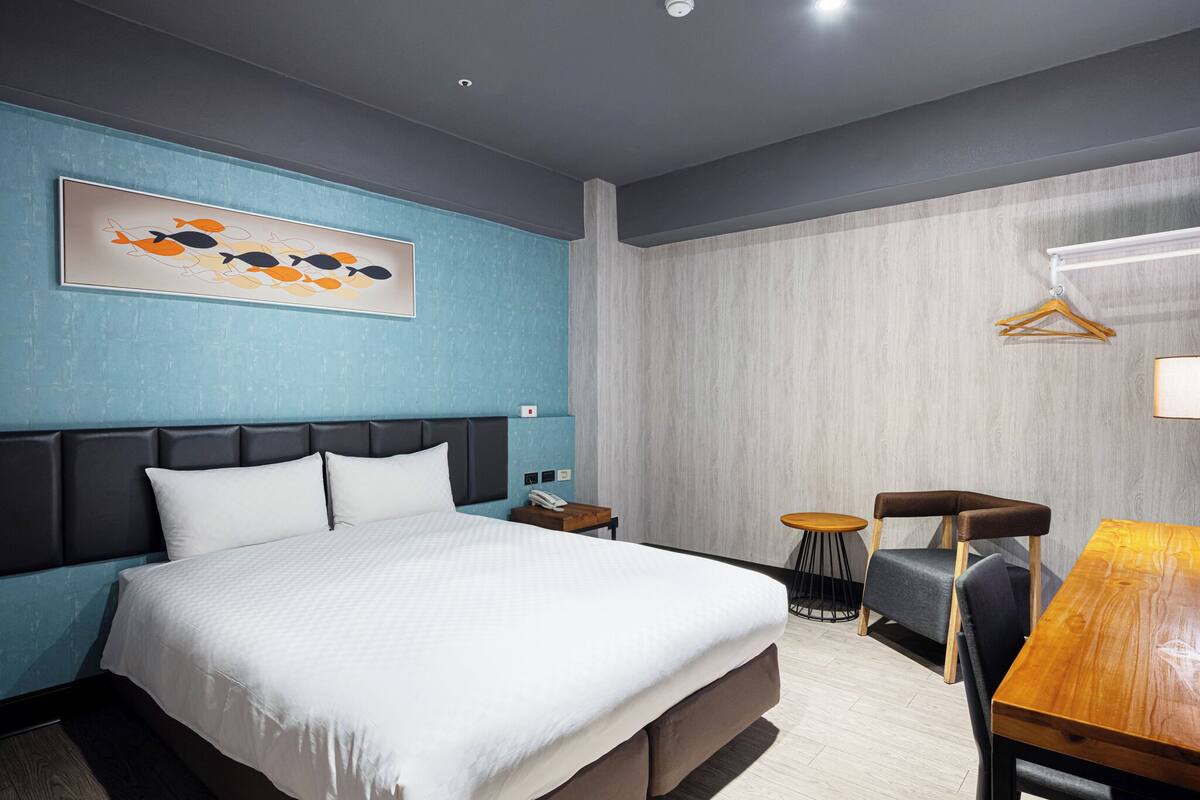 Una habitación de hotel moderna con una cama grande, un escritorio y una silla.