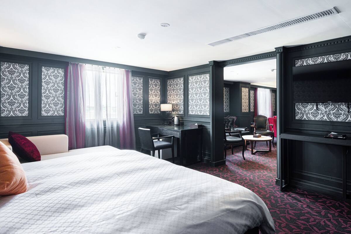 Habitación de hotel con una cama grande, un escritorio, una silla y un televisor.