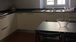 A kitchen with white cabinets, a black countertop, a stainless steel sink, and a window with blinds. - Large apartment suitable for families with children or groups (Roma)