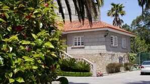 A stone building with a red-tiled roof, a small staircase, and a car parked nearby.