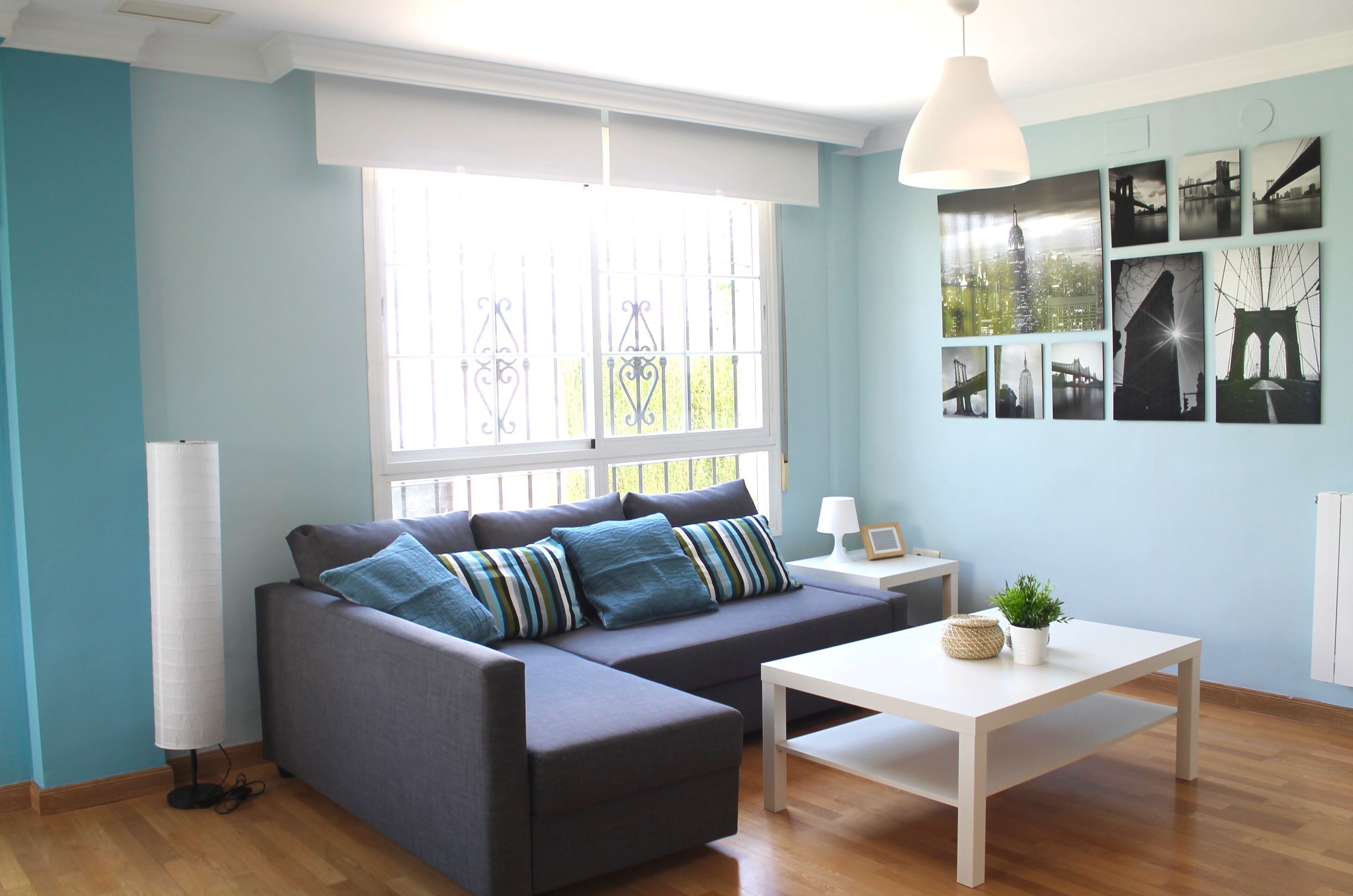 A modern living room with a sectional sofa, a white coffee table, and a cityscape wall art.
