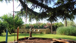 Un terrain de jeux avec une balançoire, un banc en bois et une nichoir.