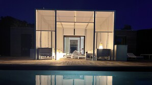 A covered outdoor seating area with a pool in the foreground. - Green house (ustica)