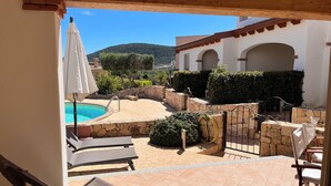 A pool area with lounge chairs, a stone wall, and a view of a mountain. - Residenza Limpiddu with Swimming Pool - Ground Floor - All Comforts  (Limpiddu)