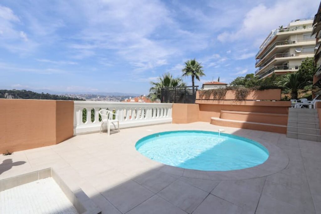 A rooftop swimming pool with a view of the city and hills in the background.