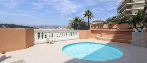 A rooftop swimming pool with a view of the city and hills in the background.