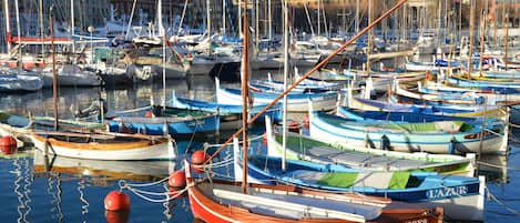 A marina with numerous boats docked, surrounded by buildings and a clear sky.