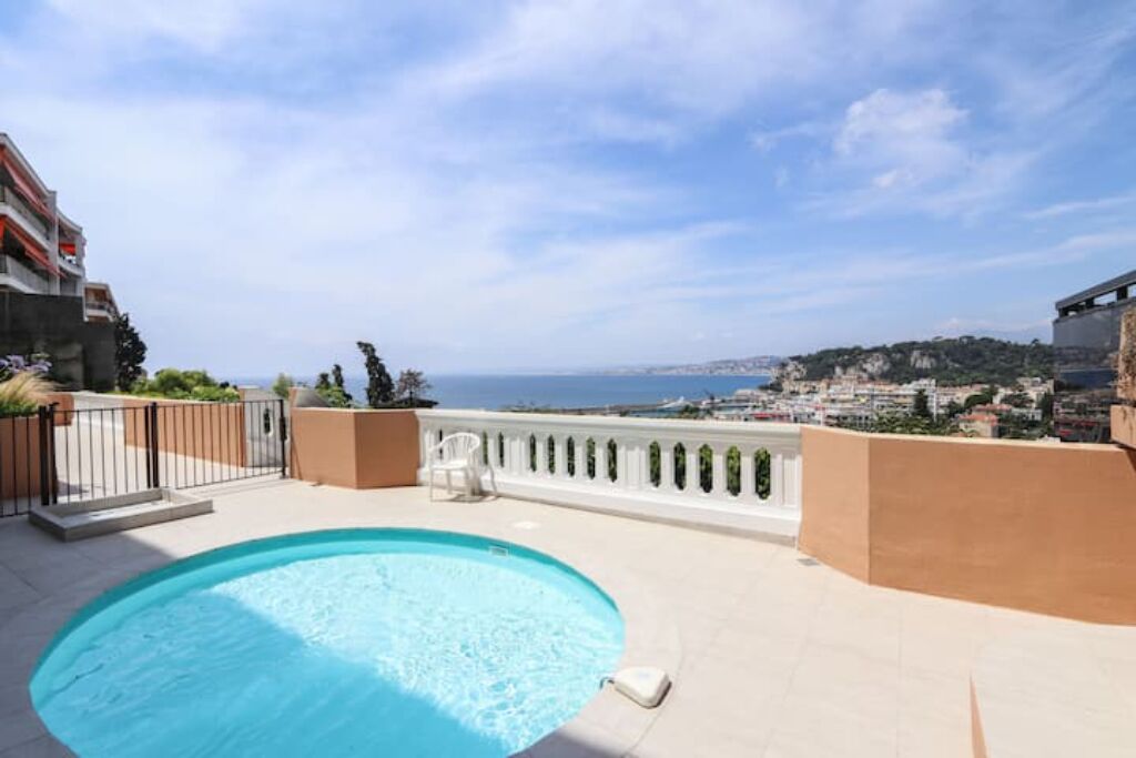 Une piscine sur le toit offrant une vue dégagée sur la mer et le paysage urbain.