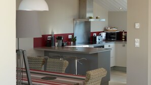 A modern kitchen with a central island, stainless steel appliances, and a hanging light fixture.