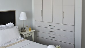 Et hotelværelse med en seng, et natbord med lampe og en stor garderobe.