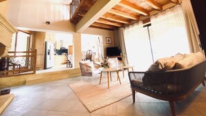 A spacious living area with a high ceiling, a sofa, a coffee table, and a television.