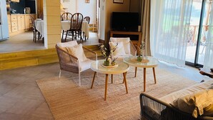 A spacious living area with a dining table, two sofas, and a television.