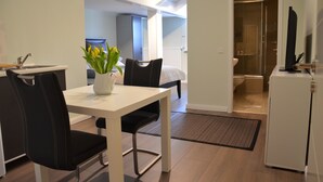 Eine moderne Küche mit weißer Arbeitsplatte, schwarzen Stühlen und einer Vase mit gelben Blumen.