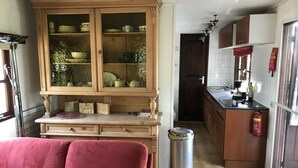 Una cocina compacta con armarios de madera, una mesa de comedor y un sofá rojo.