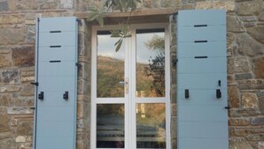 A stone building with a double door and shutters. - Casa Mancose, vacation in the olive grove with sea views in the Cilento (Cicerale (SA))