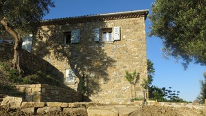 A stone building with a tiled roof, a small garden with potted plants, and a stone staircase leading up to the entrance. - Casa Mancose, vacation in the olive grove with sea views in the Cilento (Cicerale (SA))