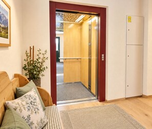 An elevator with a wooden interior, a checkered rug, and a plant on a wooden bench.