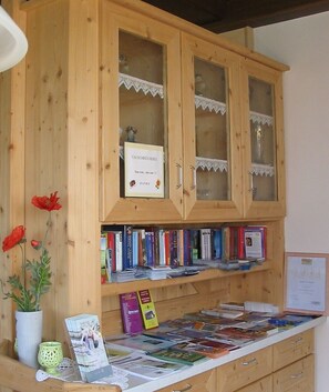 A wooden bookcase with glass doors, filled with books and a thank you card.