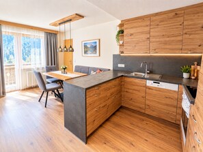 Eine moderne Küche mit Holzschnitzschränken, einer zentralen Kochinsel und einem Essbereich mit Tisch und Stühlen.