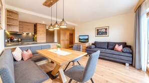 A modern living space with a dining area, sofa, and kitchen.