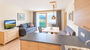 Ein modernes Wohnzimmer mit einer Couch, einem Esstisch und einer Küchenzeile mit Spüle.