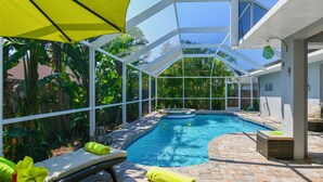 A covered outdoor swimming pool with lounge chairs and a table, surrounded by tropical plants. - Contemporary Pool Villa I - just few minutes to Beach - heated Pool & Spa, WiFi! (VENICE)