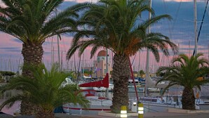 Una marina con barcos, palmeras y un edificio con cúpula al fondo.