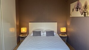 Un dormitorio con una cama grande, dos mesitas de noche con lámparas y una obra de arte en la pared.