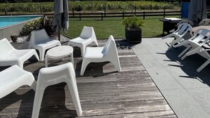 A deck with white plastic lounge chairs and umbrellas, a pool, and a view of a vineyard. - Spacious house in a quiet area with all comforts, private pool 3bed, 3bath, 3wc classified 3*. (Soustons)