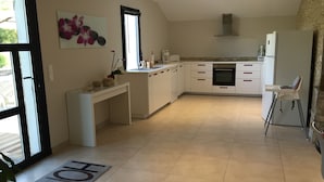 A modern kitchen with white cabinets, a built-in oven, and a dining area with a high chair. - Spacious house in a quiet area with all comforts, private pool 3bed, 3bath, 3wc classified 3*. (Soustons)