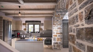 A modern kitchen with a central island, built-in appliances, and a stone accent wall. - Charlise Luxury Villa by Cretevasion (Kokkini Hani)