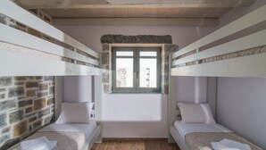 A room with two bunk beds, a stone wall, a window, and a wooden floor. - Charlise Luxury Villa by Cretevasion (Kokkini Hani)