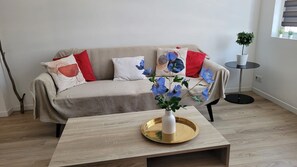 A living room with a sofa, a coffee table, and a potted plant.