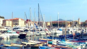 Una marina piena di diverse imbarcazioni ormeggiate in acque calme, circondata da edifici e un cielo sereno.