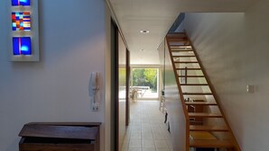 A hallway with a wooden staircase, a wooden cabinet, and a wall-mounted phone. - Air-conditioned villa with swimming pool in quiet village center with all amenities (Saint-Maurice-De-Gourdans)