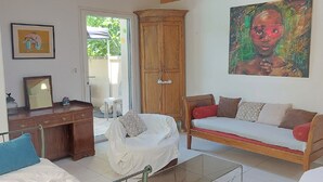 A living room with a sofa, a chair, a wooden cabinet, and a painting on the wall. - Air-conditioned villa with swimming pool in quiet village center with all amenities (Saint-Maurice-De-Gourdans)