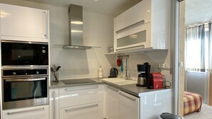 A modern kitchen with stainless steel appliances, white cabinetry, and a glass backsplash.