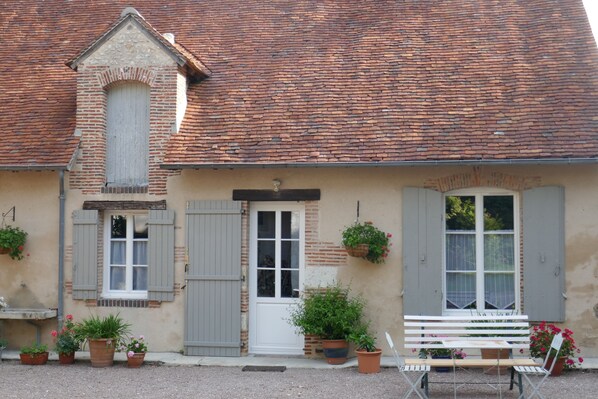 A rustic building with a tiled roof, a white door, and a bench outside. - Domaine d'Adon **** - Charming renovated house 45m² in Adon (45) sleeps 2 (Adon)