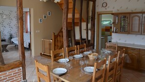 A dining area with a wooden table set for six, surrounded by wooden chairs. A staircase with wooden beams is visible in the background. - Country house 3 * comfortable 20 minutes of Wi-7 pers- wonderful garden (Carville-Pot-De-Fer)