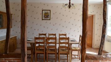 Comedor con mesa y sillas de madera, una araña y un papel tapiz estampado.
