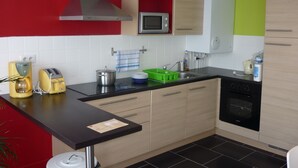 Een moderne keuken met een magnetron, broodrooster en koffiezetapparaat. Uitzicht op keukenkastjes, een spoelbak en een fornuis.